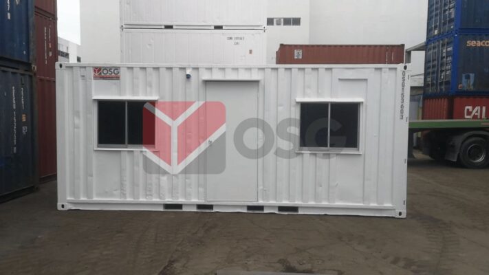 White shipping container with windows and a door, in yard.