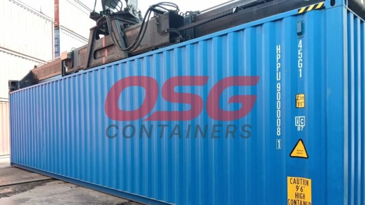 A large blue shipping container is being lifted by a crane.