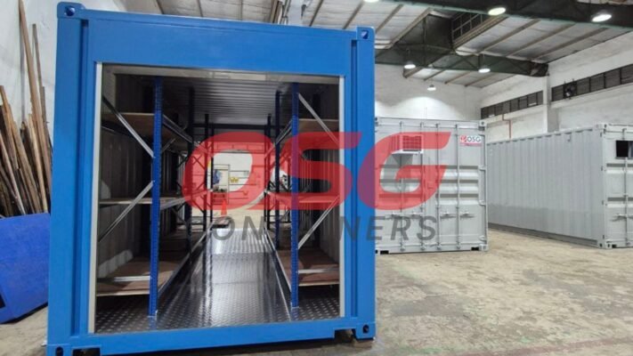 Blue shipping container with shelves inside, in a warehouse.