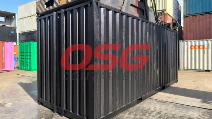 A black shipping container is in the foreground, with other containers behind.