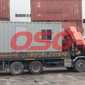 A truck with a crane is delivering a modular container.