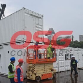 Workers install modular containers with a crane and lift.
